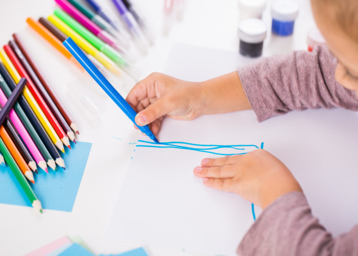 little girl drawing with colored pencils on paper