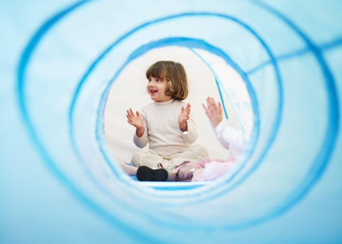 2-3 years old girls viewed from blue toy tunnel, clapping hands and singing. Horizontal shape, Copy space
